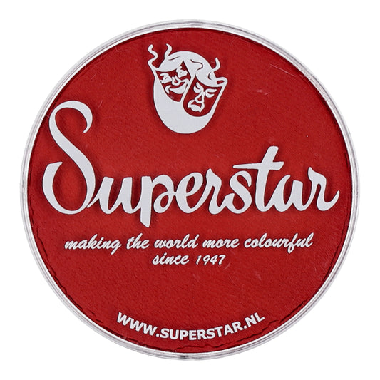 A red circular logo displays Superstar in white cursive, with making the world more colourful since 1947 beneath. A crest with theatrical masks is at the top, while the bottom shows WWW.SUPERSTAR.NL, highlighting Infinity Faces cruelty-free Aqua Face & Body Paint in Fire Red (16g).