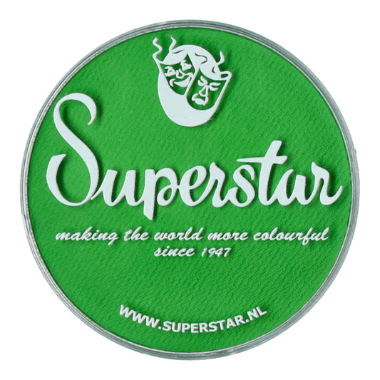 A round green lid displays Superstar in white script with comedy and tragedy masks. Beneath, it says, making the world more colourful since 1947. Explore our cruelty-free Infinity Faces Aqua Face & Body Paint in Poison Green at WWW.SUPERSTAR.NL.