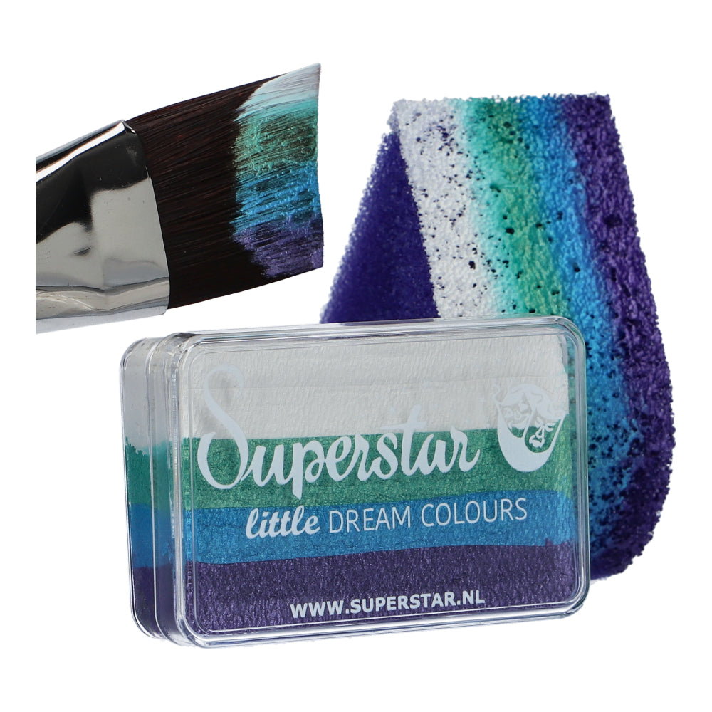 A paintbrush with purple, blue, and white strokes lies beside a textured sponge in matching hues. Below them, a compact labeled Face Paint & Body Paint Aqua Superstar - Little Mermaid (One Stroke) (30gr) by Infinity Faces showcases child-friendly water-based makeup in these colors.