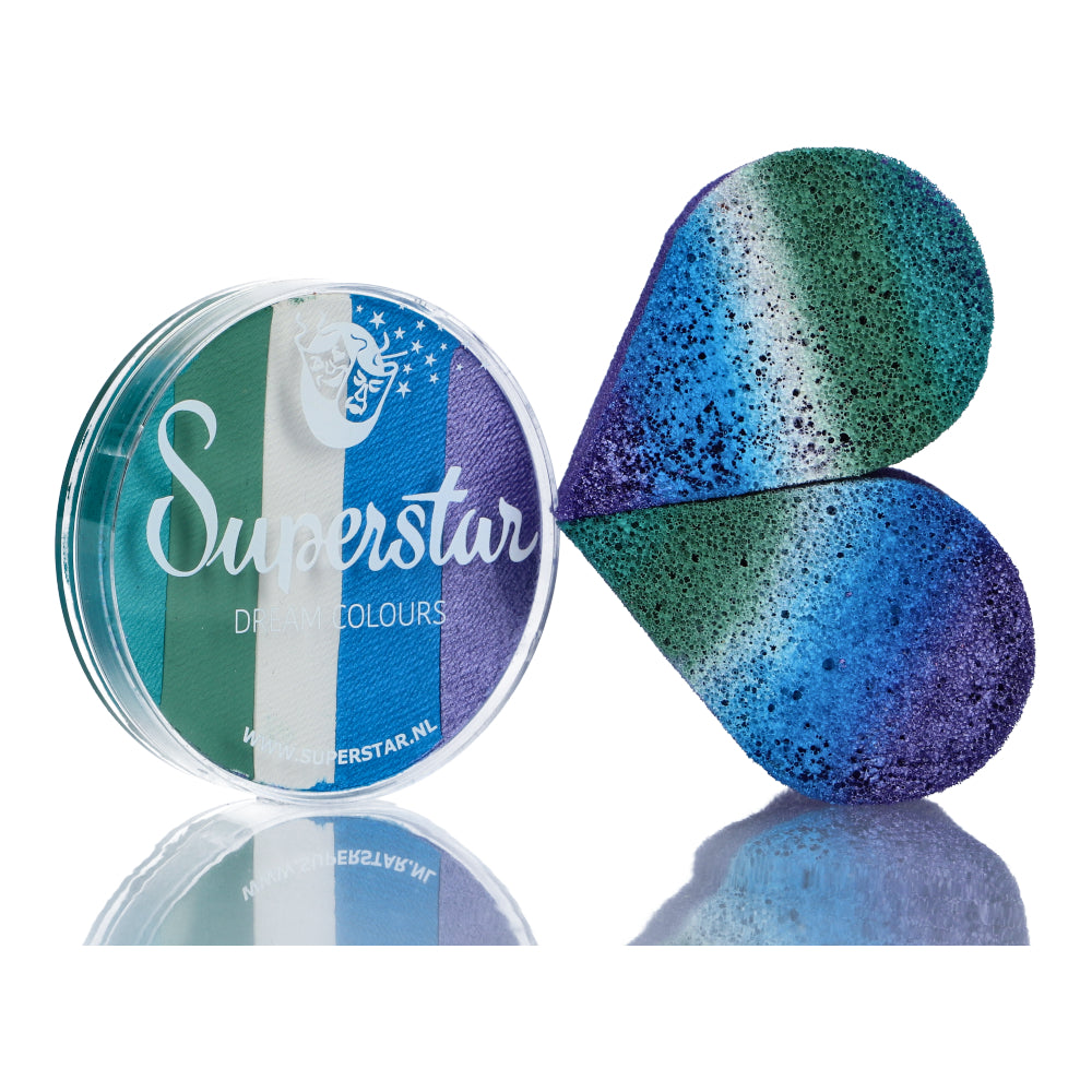 An open round container of Split Cake Dream Colour Superstar - Mermaid (45gr) from Infinityfaces reveals a multicolored makeup sponge. This Aqua Face and Bodypaint displays blended shades of green, blue, and purple shaped like butterfly wings on a reflective surface.