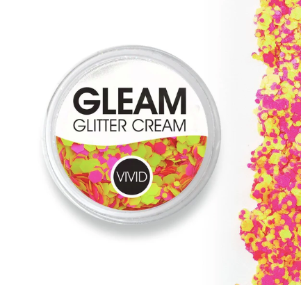 A round container labeled Infinity Faces Glitter Cream Gleam - Antigravity UV (10g) holds chunky neon pink and yellow glitter. Some glitter is scattered in a line to the right of the container on a white background.