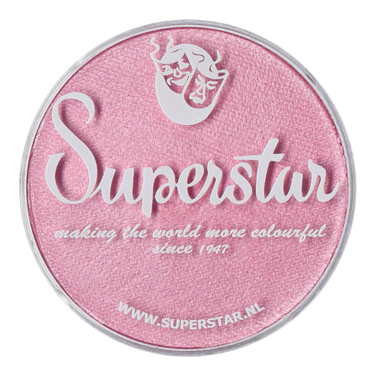 A round pink makeup container features Superstar in white script and making the world more colourful since 1947. Above it is a stylized face and mask logo. This cruelty-free, water-based aqua face and body paint by Infinity Faces details its website WWW.SUPERSTAR.NL at the bottom.