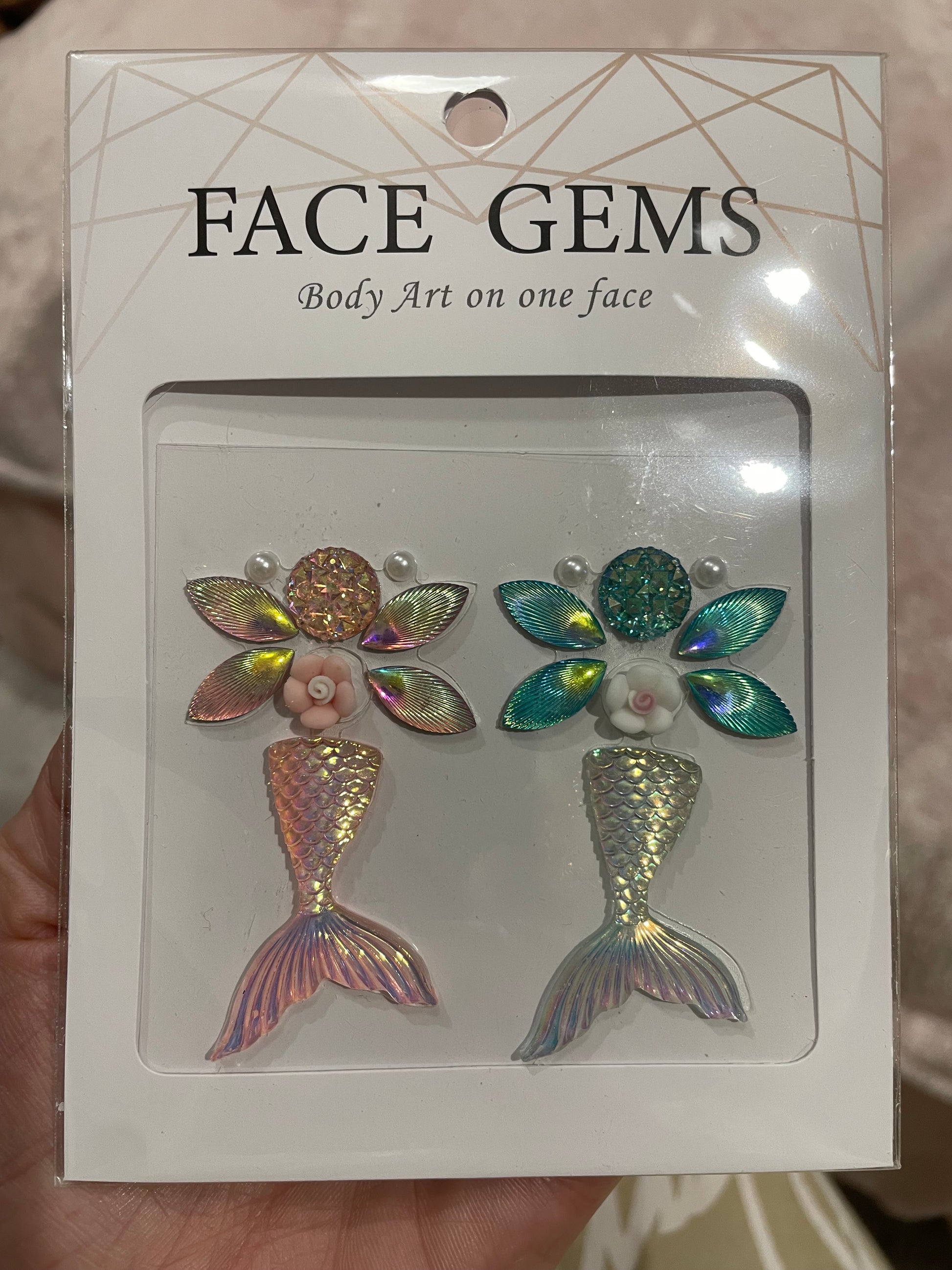 Infinityfaces Face- & Body Gems - Mermaid features mermaid-themed decorations with iridescent tails, flowers, and leaves, along with the text Body Art on one face. Made with reusable adhesive for easy application and removal.