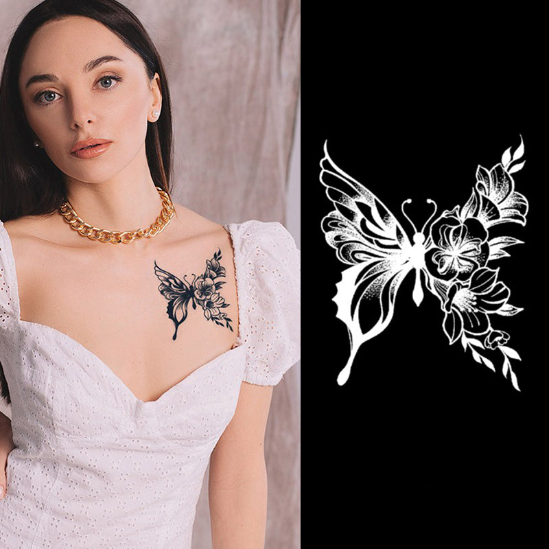A woman in a white dress showcases Infinityfaces Temporary Herbal Tattoo - Flower Butterfly, adorned with floral elements and presented with a gold chain necklace. On her right, the dark background highlights a black and white illustration celebrating this plant-based tattoo artistry.