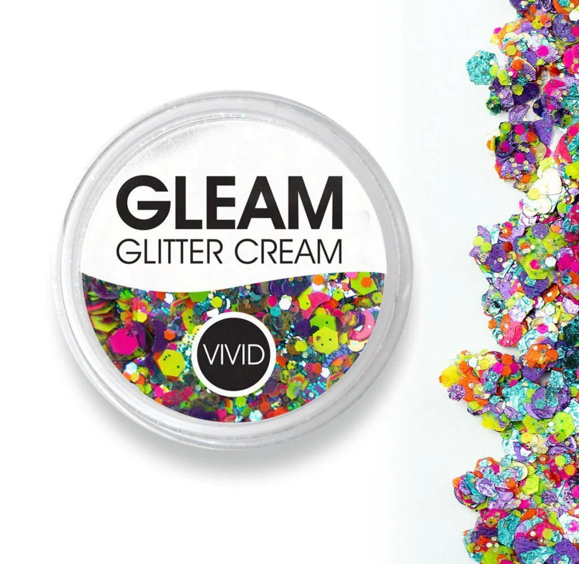 An open container labeled Gleam Glitter Cream Fusion - Aloha from Infinity Faces reveals an array of vibrant, chunky glitter spilling to the right, showcasing a colorful mix of various shapes.