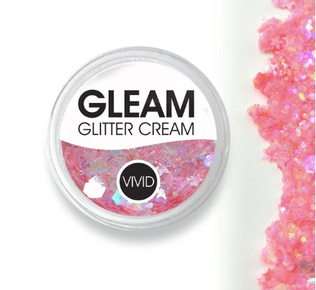 A container labeled Glitter Cream Gleam - Mystic Melon (10g) by Infinity Faces with vibrant pink iridescent glitter cream, shown next to a swatch of the same pink glitter spread on a white background.