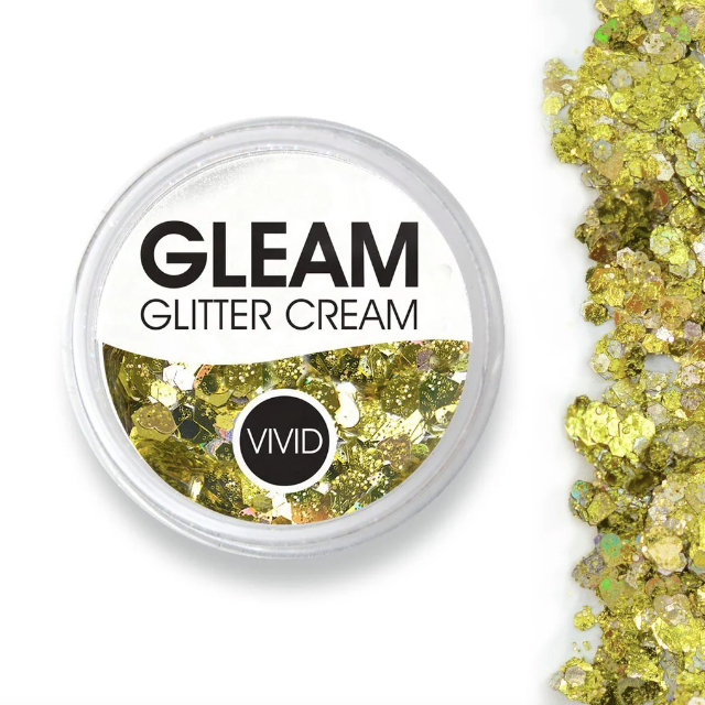A round container labeled Infinity Faces Glitter Cream Gleam - Treasure (10g) holds chunky gold glitter, with some glitter scattered beside it on a white background.