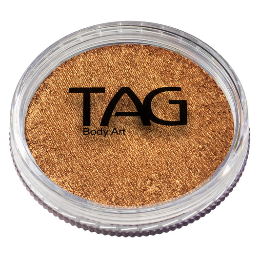 A round, clear plastic container filled with TAG Face & Body Paint - Pearl Old Gold (32g), featuring shimmering water-activated face and body paint.