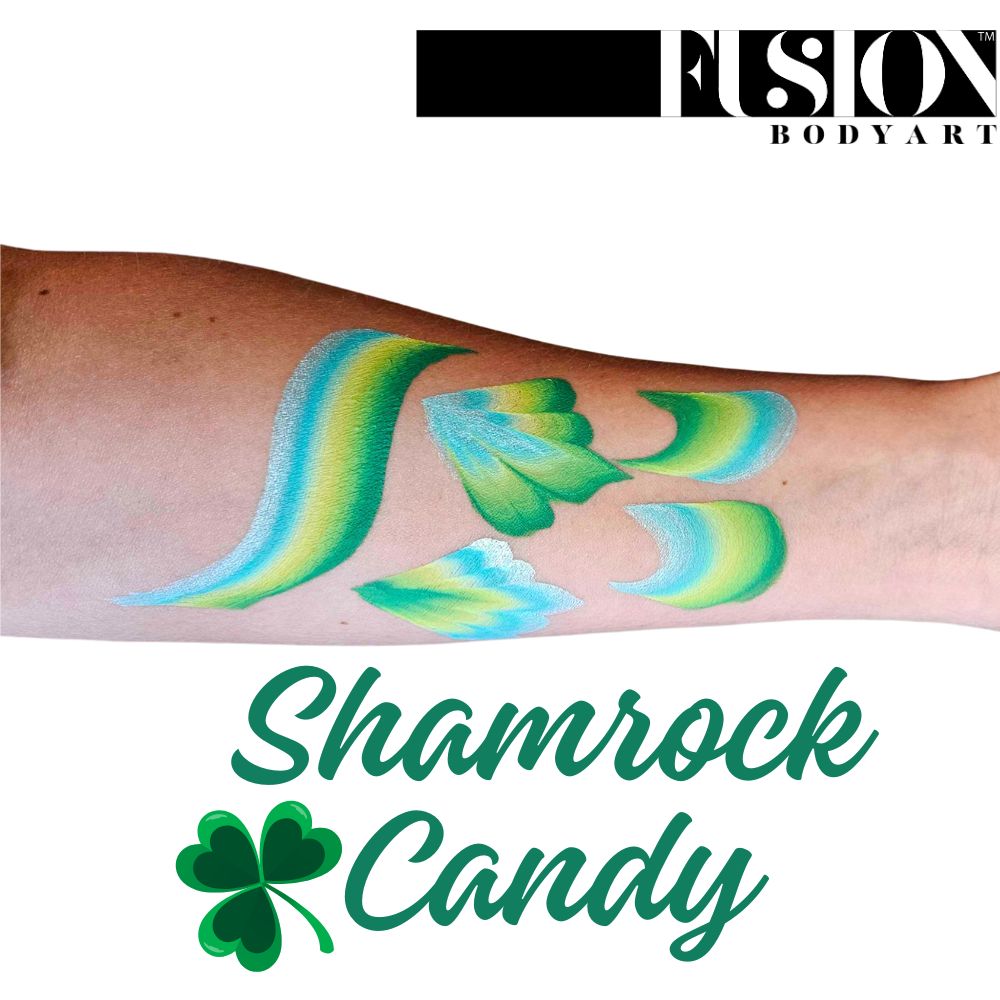 A forearm shows green, yellow, and blue face paint strokes like clover leaves. Above is the Infinityfaces logo; below, green script reads Face Paint & Body Paint Aqua Fusion - Shamrock Candy (One Stroke) (30g) with a shamrock graphic.