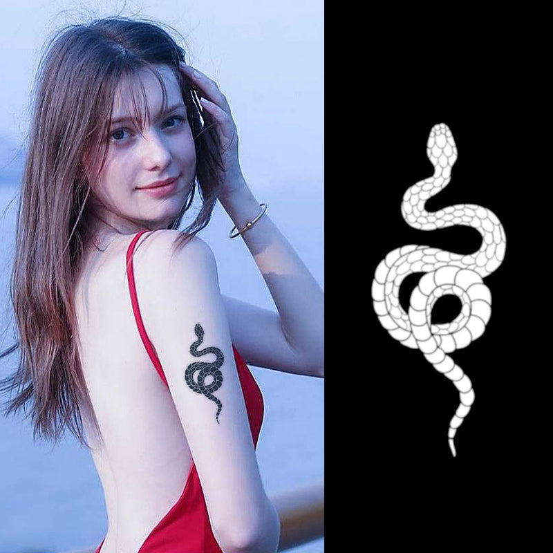 A woman in a backless red dress flaunts a black snake tattoo on her upper arm, made with Infinityfaces Temporary Herbal Tattoo - Snake. Her long brown hair cascades down as she touches it with one hand, standing beside an illustration of a white snake on a black background.