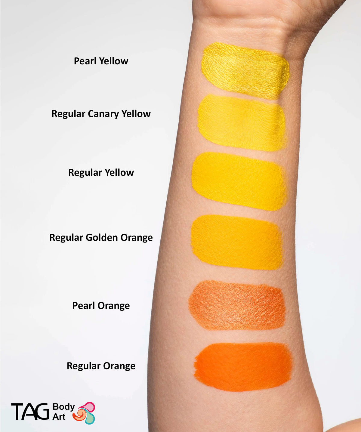 A forearm displaying six swatches of TAG Face & Body Paint - Pearl Orange (32g) and other shades, labeled from top to bottom as Pearl Yellow, Regular Canary Yellow, Regular Yellow, Regular Golden Orange, Pearl Orange, and Regular Orange.