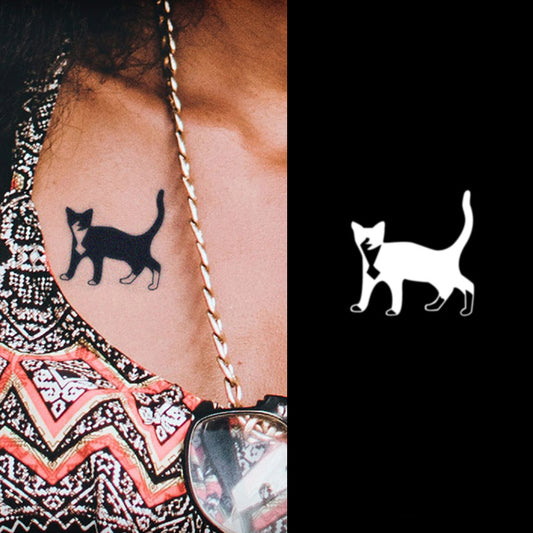 Adorning a shoulder, The King of Cats temporary herbal tattoo by Infinityfaces features a minimalistic black cat design. It contrasts with a zigzag patterned colorful shirt and mirrors a white version on black ink, using skin-safe ink to ensure lasting vibrancy and gentleness on the skin.