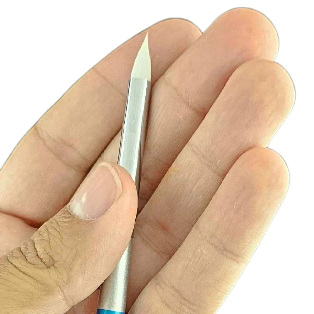 A close-up of a hand holding the Infinity Faces Brushes Bolt - Diamond Collection - Fresh Petal, featuring a white, pointed chisel-like tip, positioned against the palm and fingers.