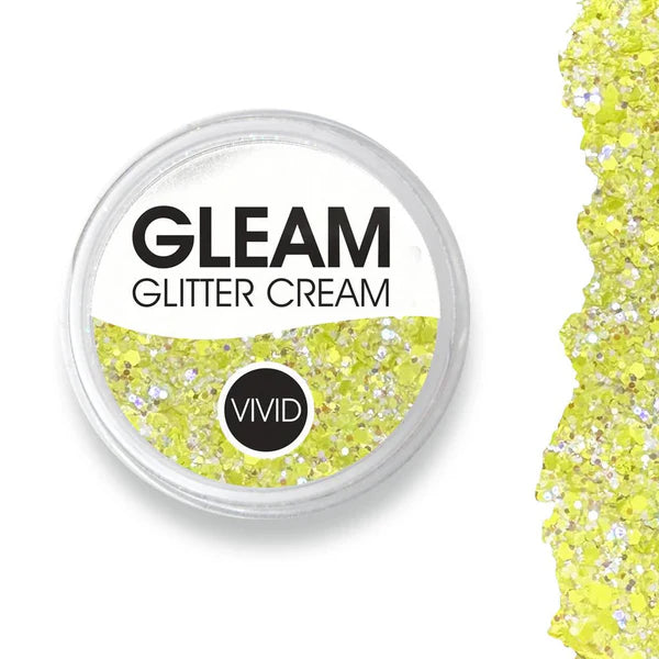 A round container labeled Infinity Faces Glitter Cream Gleam - Sunbeam (10g) NEW, filled with yellow and silver glitter, is shown next to a scattered pile of the same glitter.